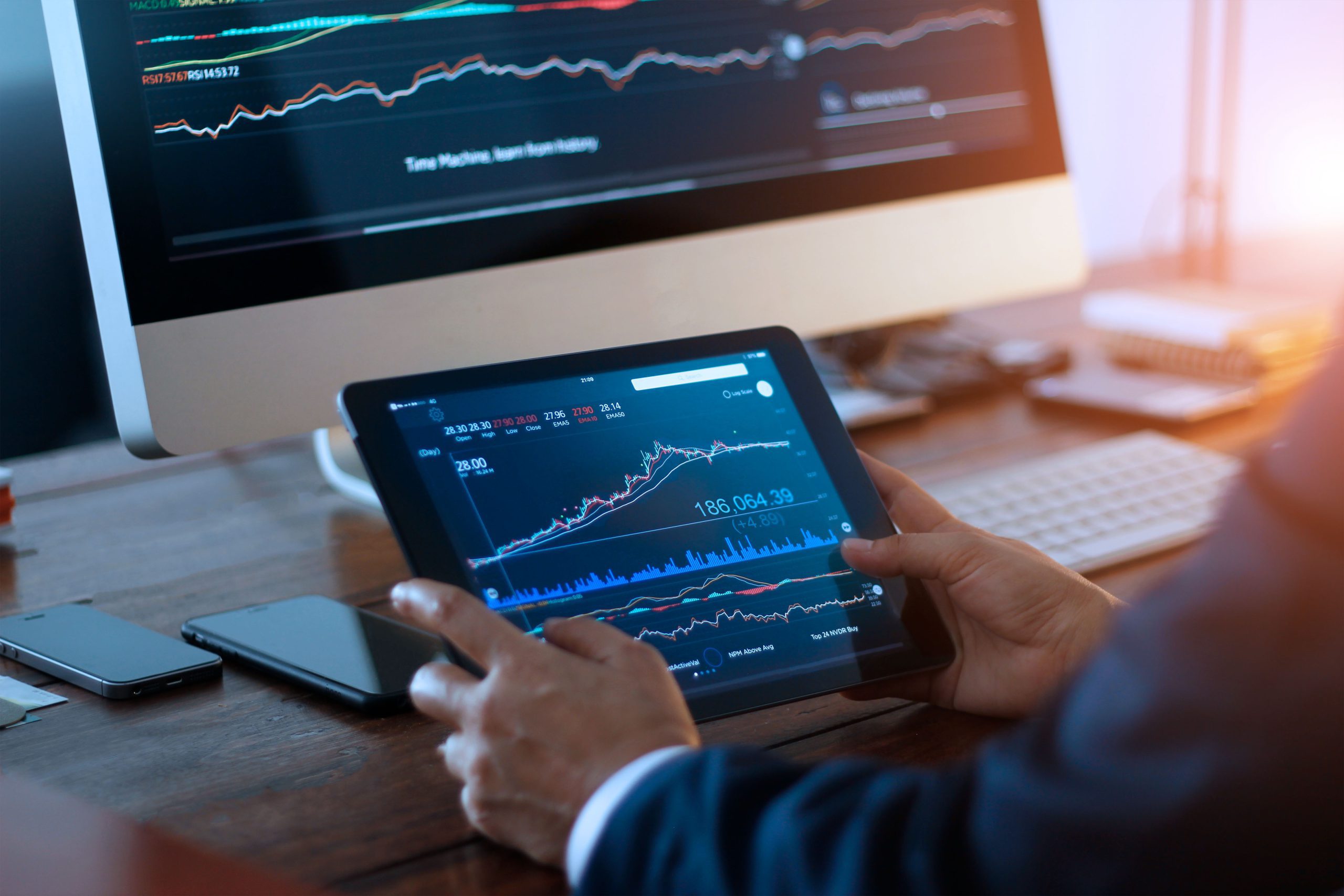 Businessman checking stock market on digital tablet and a deskto
